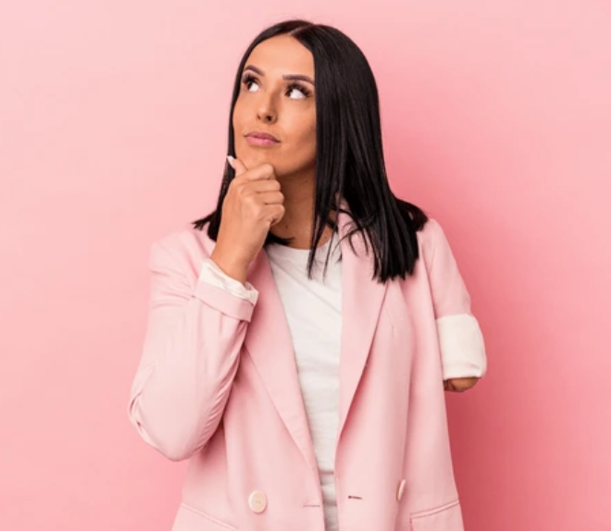 A woman with a limb difference wears a pink blazer over a white t-shirt